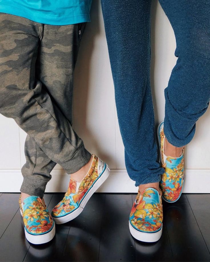 Two pairs of feet wearing colorful slip-on shoes against a white wall. - Thread Vision Client Spotlight, Goldfish Kiss