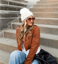 Load image into Gallery viewer, Woman wearing a brown cropped moto jacket, white beanie, and sunglasses sitting on steps. - Thread Vision Spotlight, Hill x Sarah, Sarah Hill 
