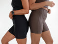 Load image into Gallery viewer, Two people wearing black and brown athletic shorts on a white background - Thread Vision Spotlight, Day 1 Fitness, Kaylee Rogers 
