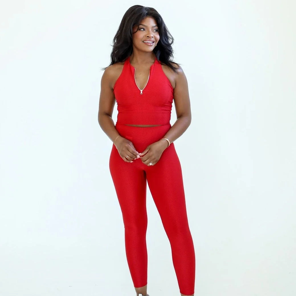 Woman wearing a red sports bra and red leggings outfit on a white background - Thread Vision Spotlight, Day 1 Fitness, Kaylee Rogers 