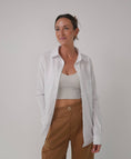 Load image into Gallery viewer, Woman wearing a white shirt over a gray top and brown pants on a plain background - Thread Vision Spotlight, Loe Hayley
