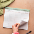 Load image into Gallery viewer, Hand holding a planner with meal planning sections on a wooden surface - Thread Vision Spotlight, Oh Snap Macros
