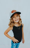 Load image into Gallery viewer, Young girl wearing a black tank top, blue jeans, and a cap with a brown patch on a light gray background - Thread Vision Client Spotlight, Cheerfully U by Alyssa Webster 
